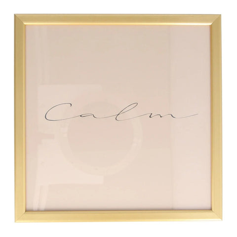 A square 'Calm' gold framed print.The word calm is in a simple black script font, across a dusky pink background. It has a simple elegant gold frame.